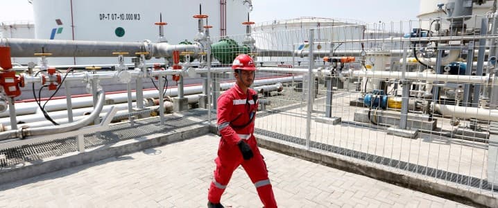 Pertamina employee walking past fuel tanks
