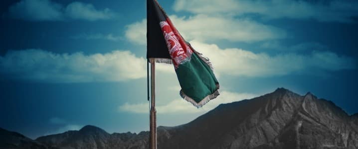 Afghan flag on a rock with a mountain range in the background